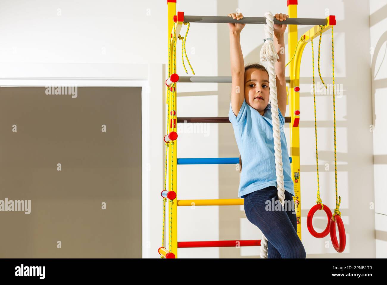 Beautiful athletic girl plays sports on Wall bars in the children's ...