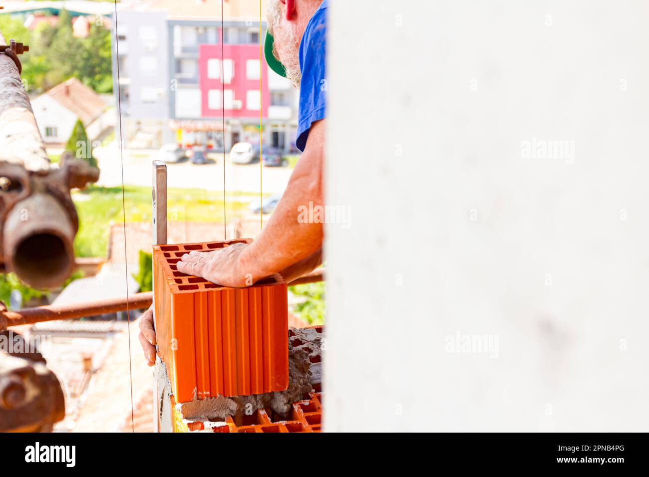 Builder is using a spirit level to check new red brick wall made of red ...
