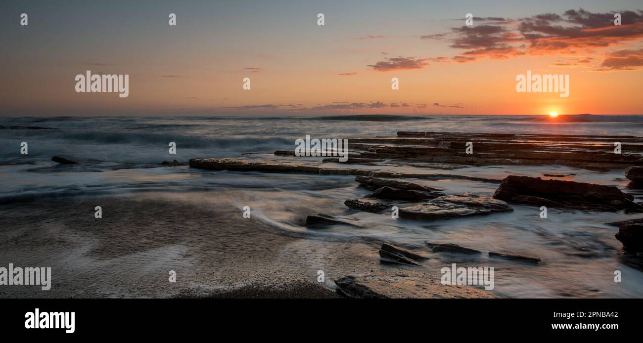Dramatic beautiful sunset on a rocky coast. Bright sun light on the horizon Stock Photo
