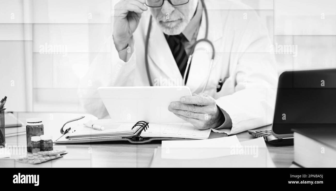 Male senior doctor using digital tablet in medical office, geometric pattern Stock Photo