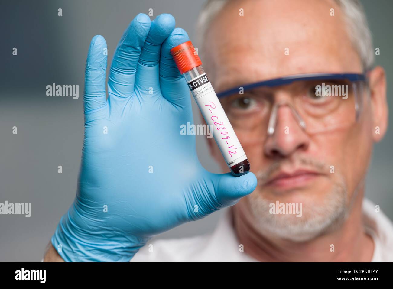 doctor or scientist is handling a blood test tube in front of a lab