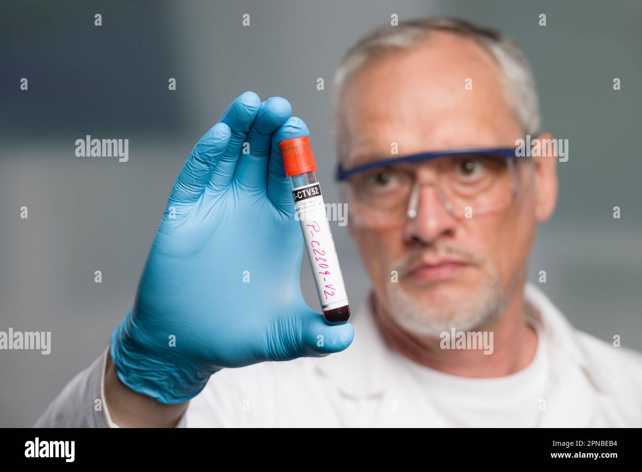 doctor or scientist is handling a blood test tube in front of a lab