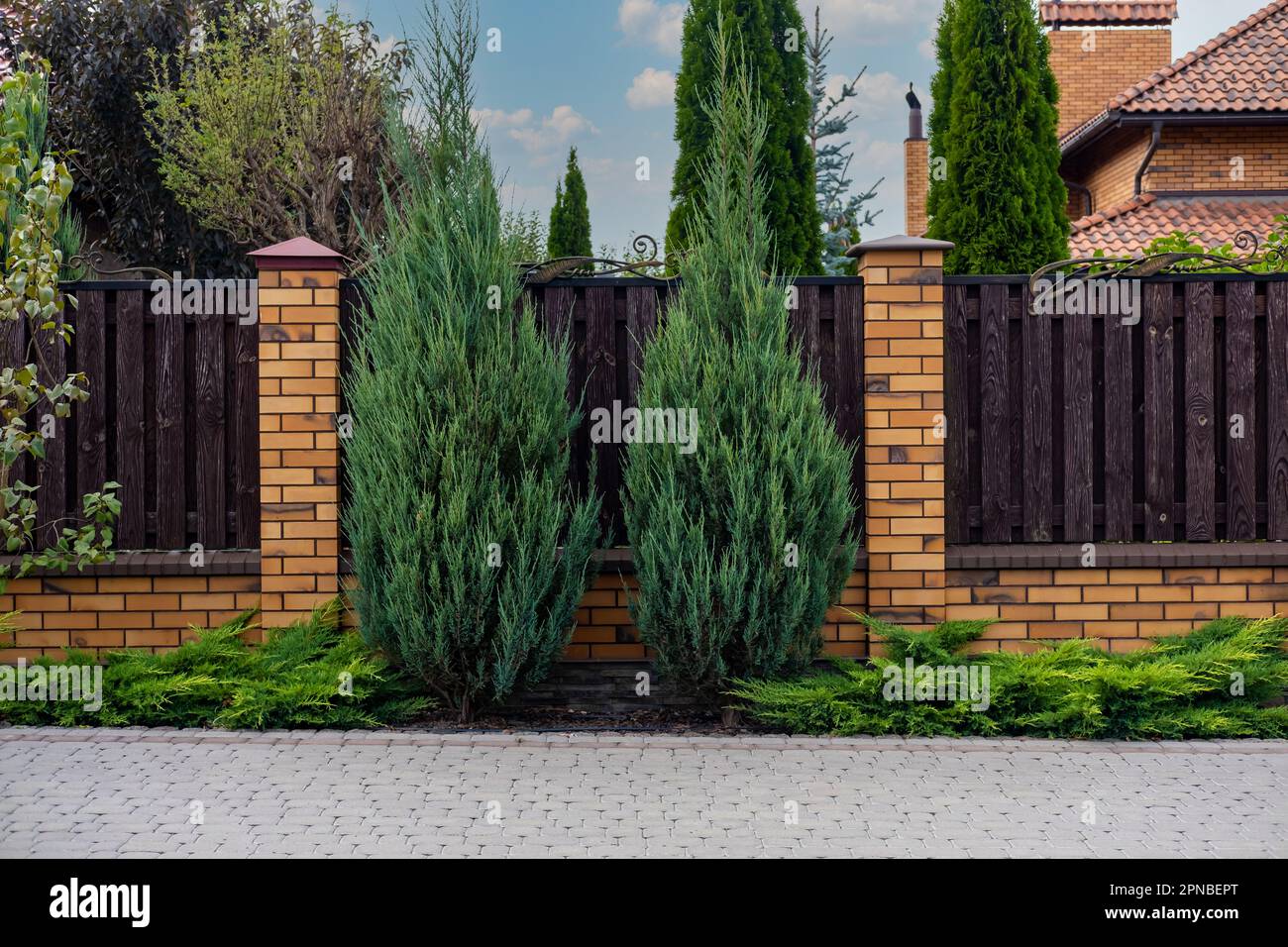 Beautiful decorative modern wooden fence with brick columns Stock Photo