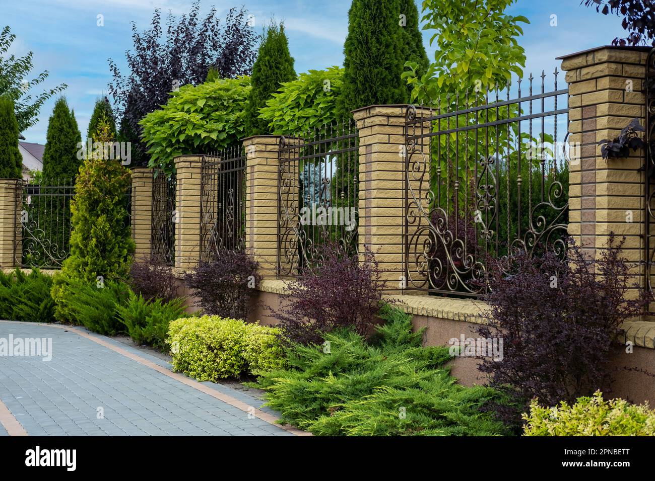 Iron wrought-iron fence between decorative brick columns in front of a