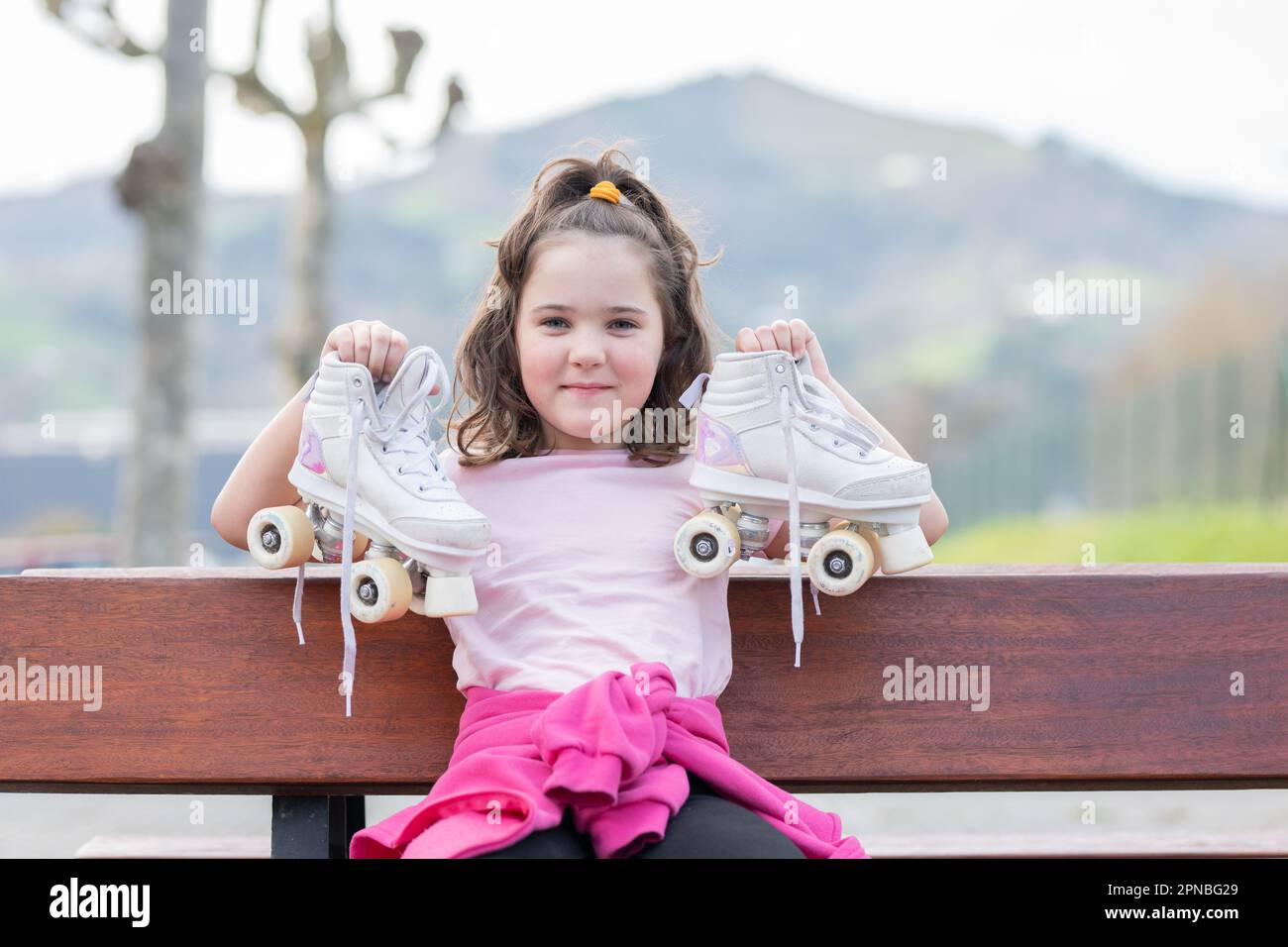 Positive girl child with jacket tied around waist relaxing on bench