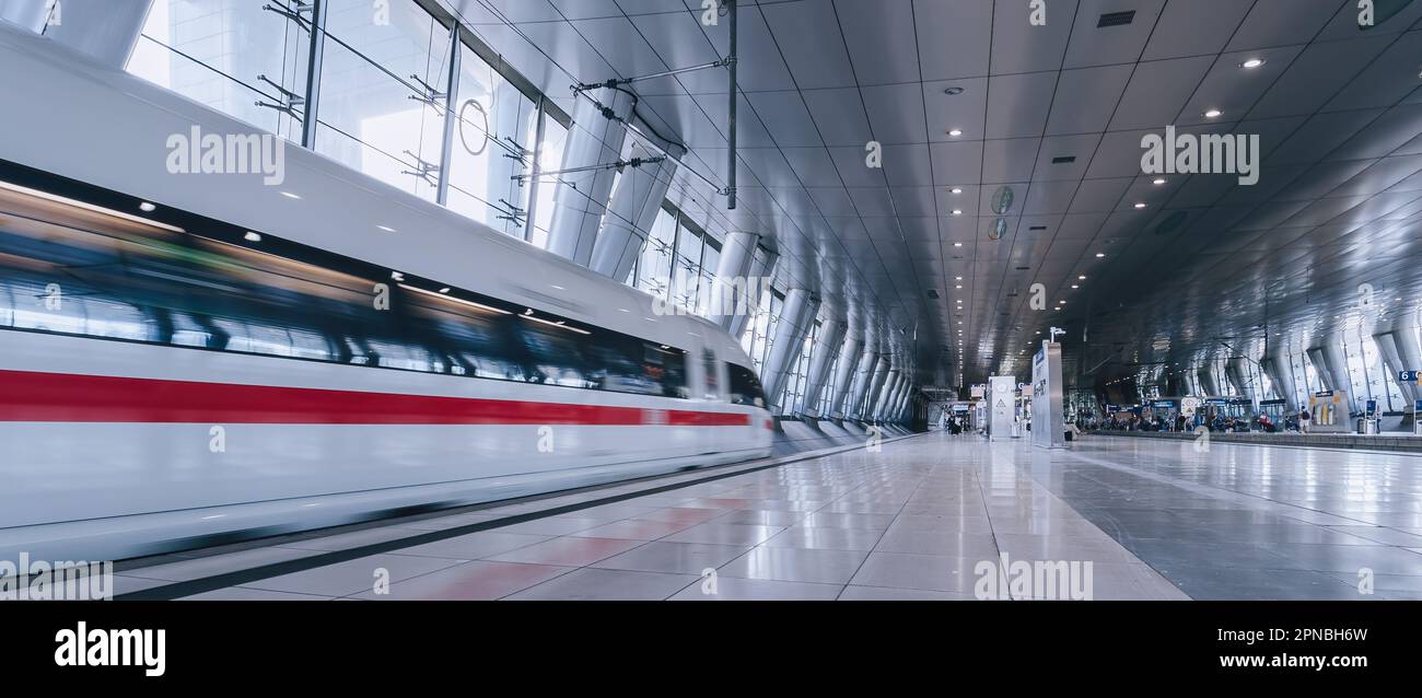 A high-speed passenger train rushing through a bustling airport ...