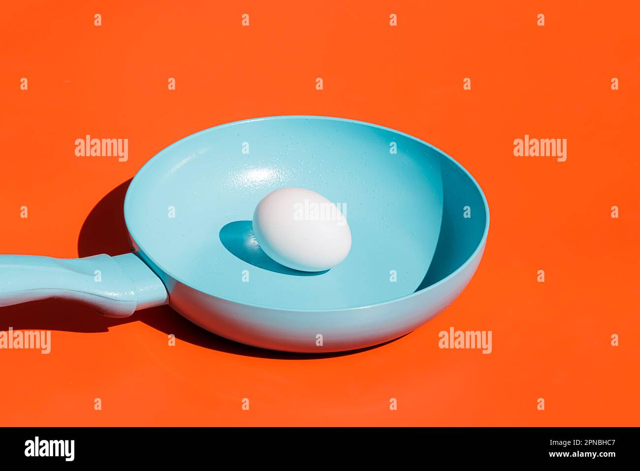 https://c8.alamy.com/comp/2PNBHC7/whole-raw-egg-placed-on-blue-ceramic-frying-pan-isolated-against-bright-orange-background-2PNBHC7.jpg