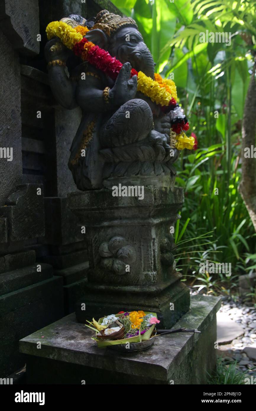 Traditional Ganesha statue with flower wreath in Balinese garden. Lord