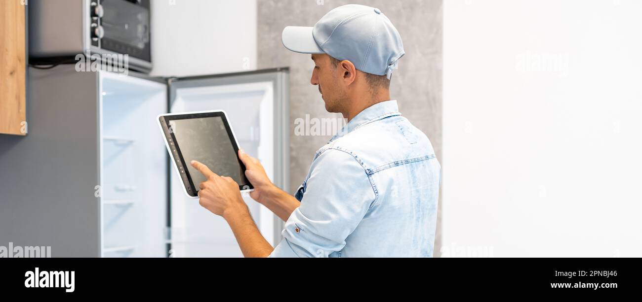 Male worker types on a tablet, kitchen renovation Stock Photo
