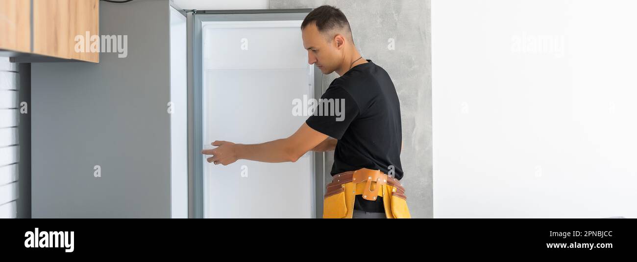 Young Male Technician Checking Fridge With Digital Multimeter Stock Photo