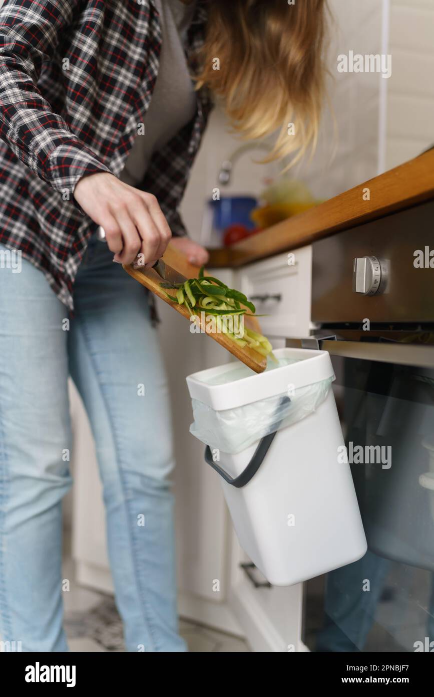 Throwing Compost Woman throwing compostable food peels in a bokashi bin with compost and ...