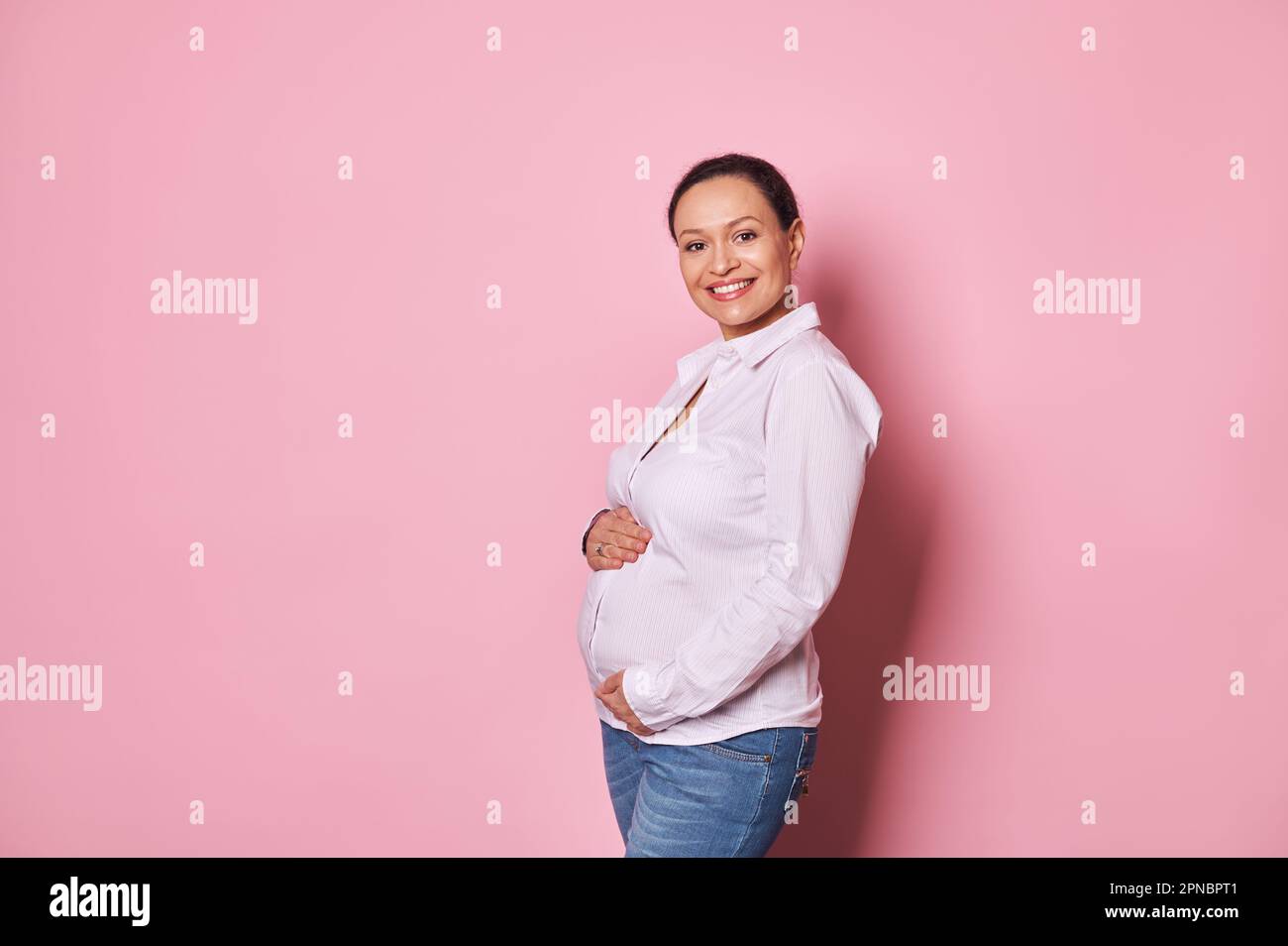 Multi ethnic pregnant woman, touching her belly, enjoying first baby