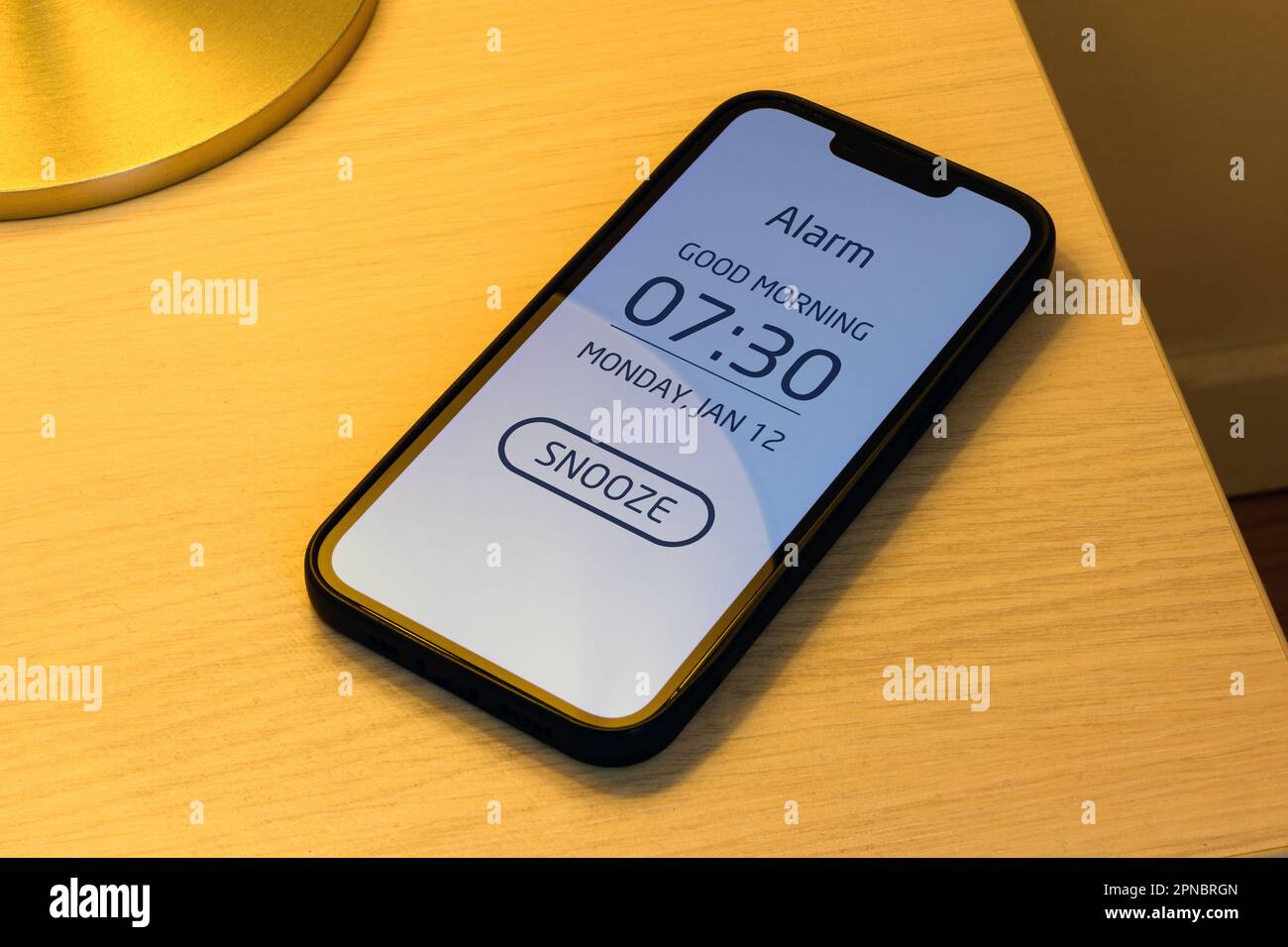 Smartphone alarm clock on bedroom night table with snooze button, selective focus Stock Photo