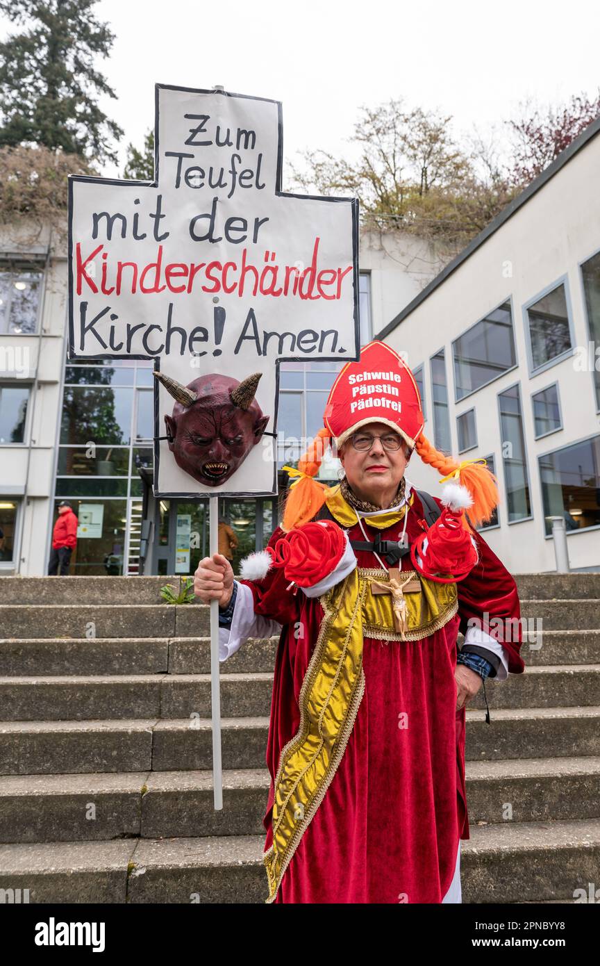 Freiburg Im Breisgau, Germany. 18th Apr, 2023. A man holds a sign outside the Catholic Academy before the start of a press conference by the Archdiocese of Freiburg on dealing with abuse that reads 'To hell with the child molester church! Amen.' The report on the previous handling of sexualized violence was compiled by independent experts. Credit: Silas Stein/dpa/Alamy Live News Stock Photo
