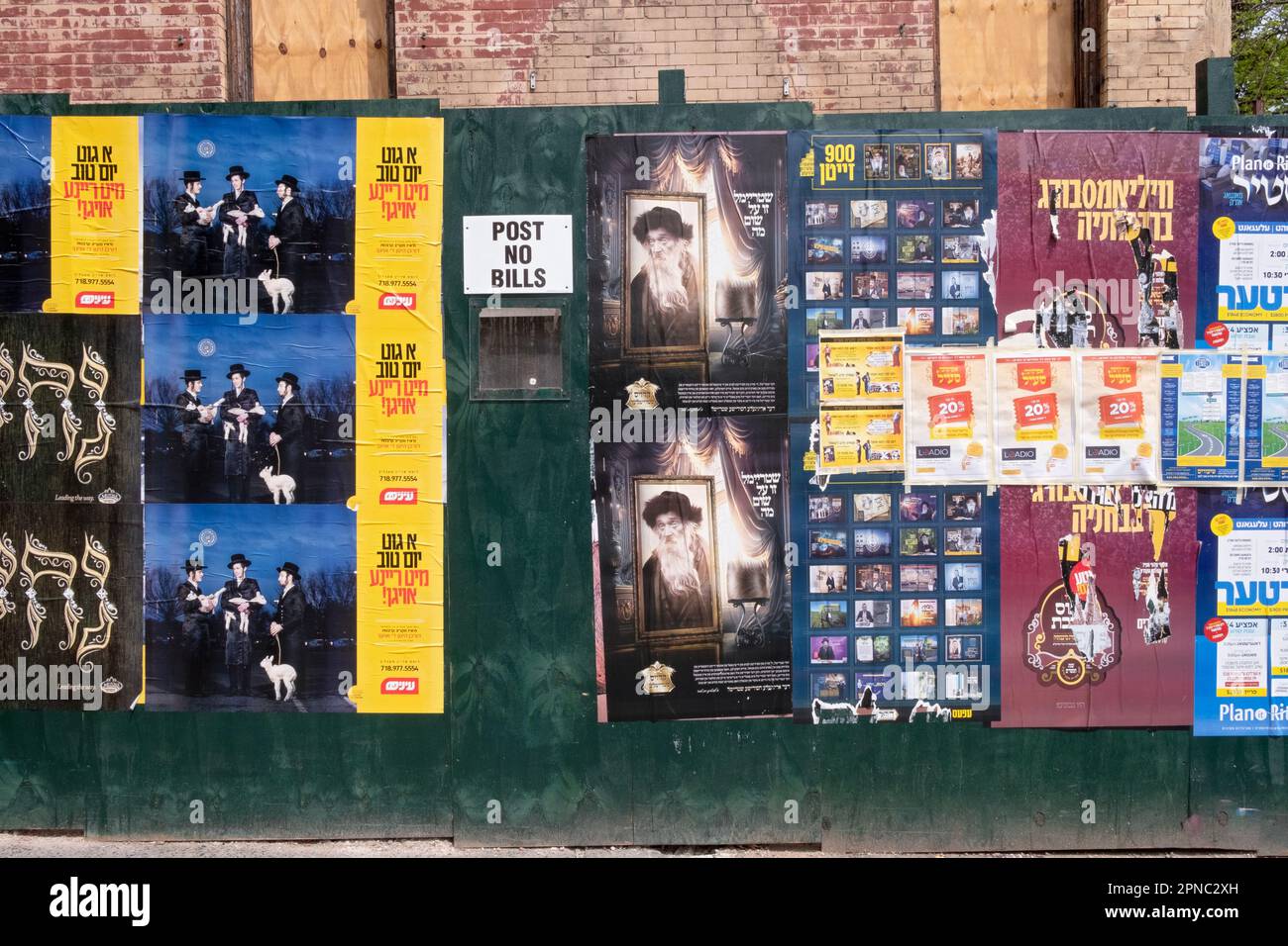 A fence at a construction side filled with advertisements primarily in Yiddish, seemingly in disregard for the sign saying Post No Bills. In New York. Stock Photo