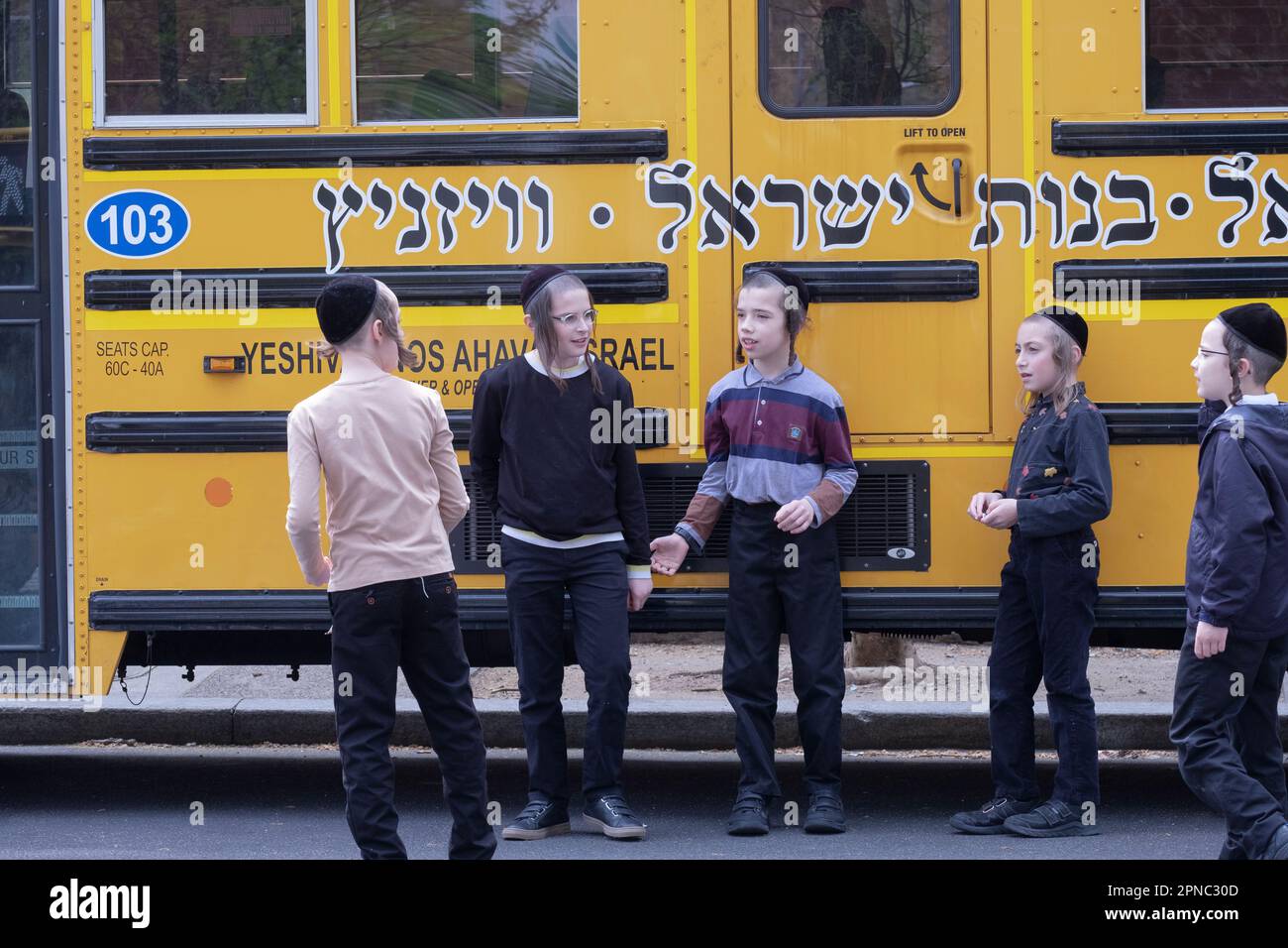 Orthodox Jewish schoolmates hang out during recess on a mild spring day. In New York City. Stock Photo