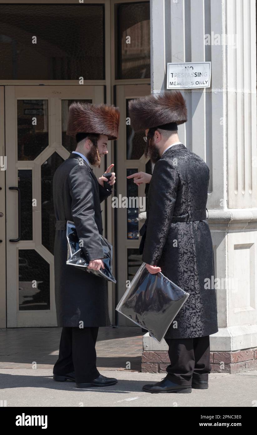 2 orthodox Jewish men wearing shtreimel fur hats have an animated conversation outside a Satmar synagogue in Brooklyn, New York. Stock Photo
