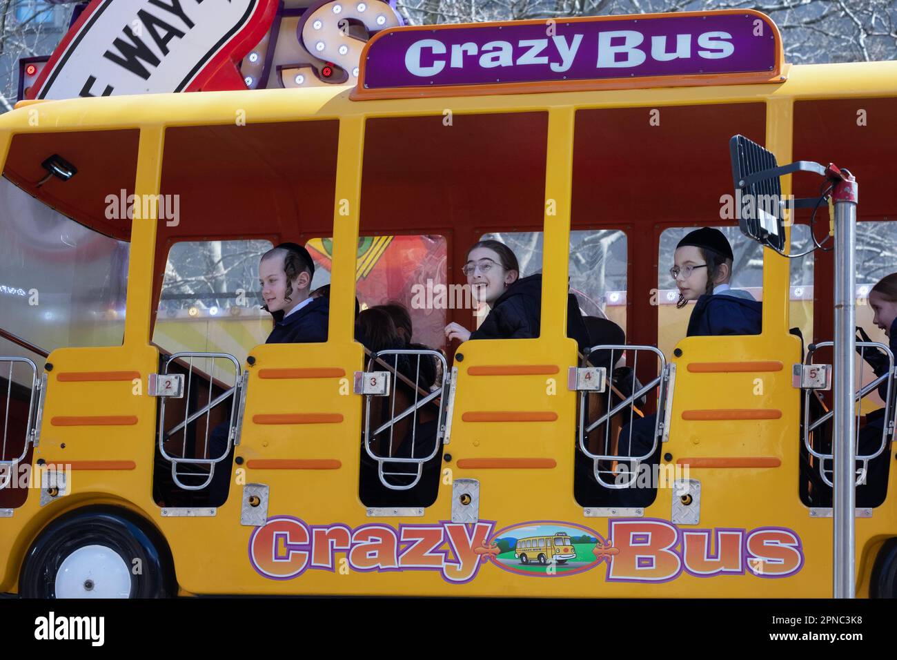 During Passover when it's mandated to have fun, Hasidic children ride the Crazy Bus at a temporary outdoor amusement park in Williamsburg, Brooklyn, N. Stock Photo