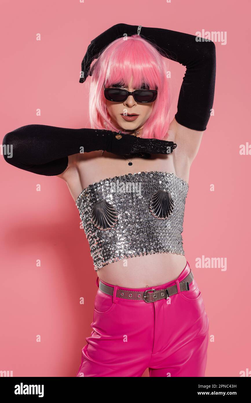 Portrait of drag queen in sunglasses and shiny silver top posing on pink background,stock image Stock Photo