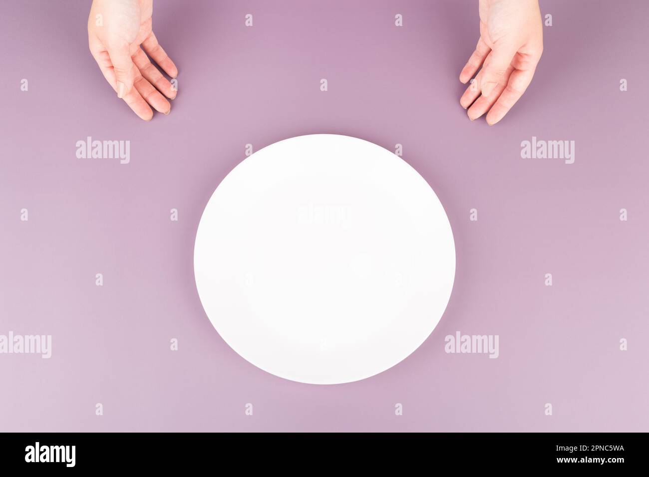 Female hands present an empty plate of food. Background for restaurant advertising Stock Photo