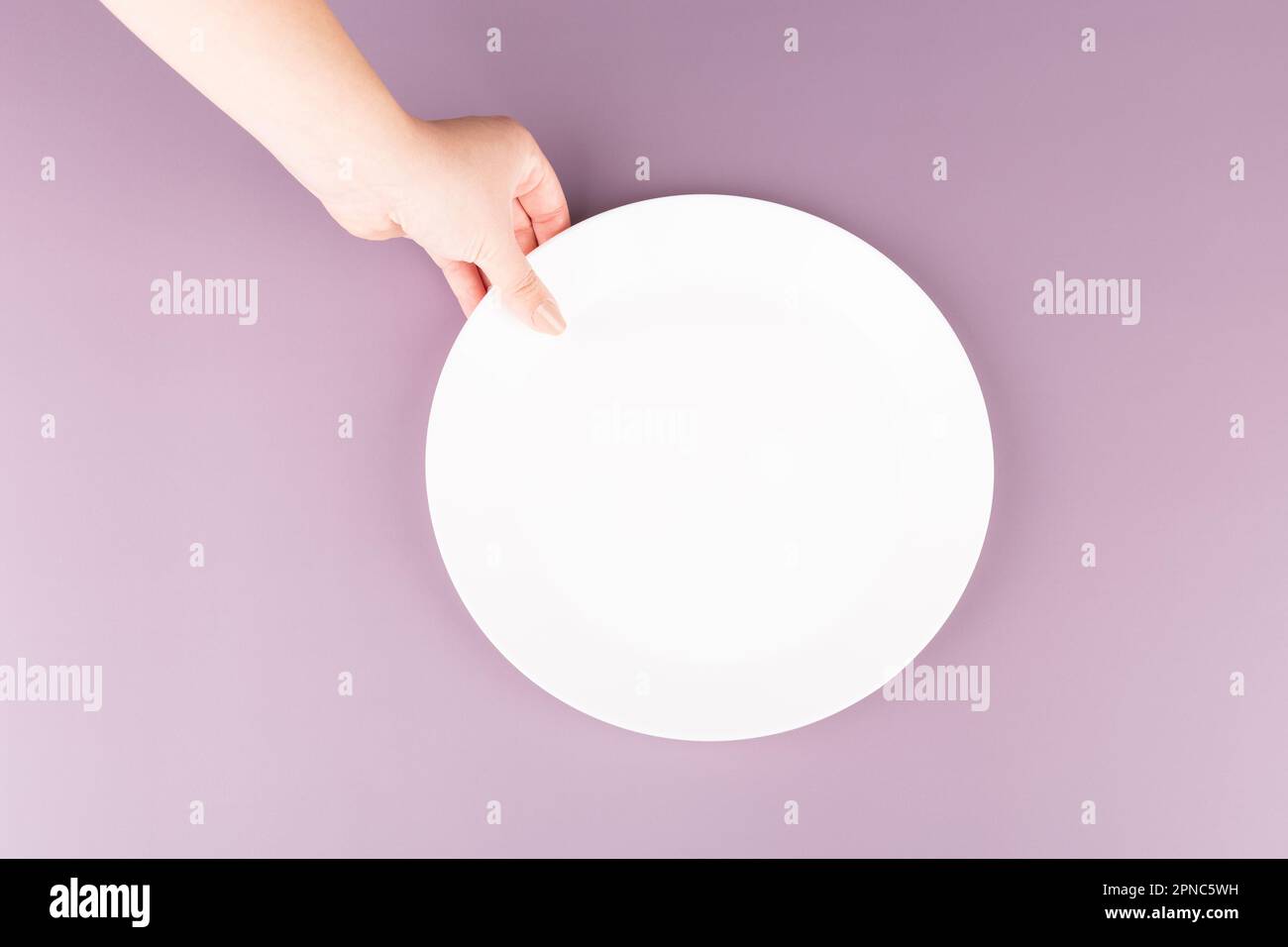 A hand holds an empty plate of food. Background for restaurant advertising Stock Photo