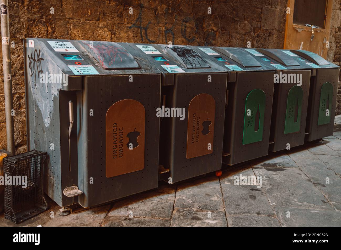 Metal iron trash bins sit on cement driveway beside the house in front