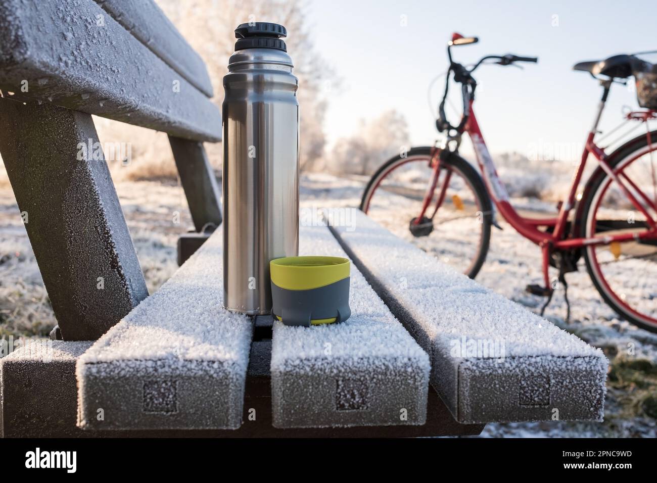 Thermos and Mug with Hot Drink Standing on Wet Wooden Table after