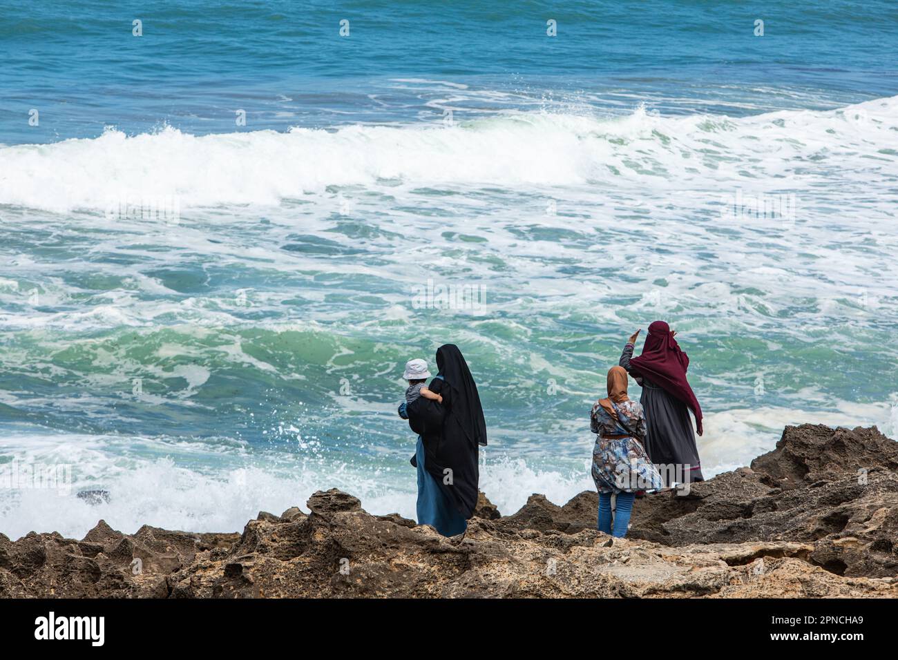 Tangier, Morocco 2022:  people in the beach near  Caves of Hercules in Cape Spartel Stock Photo