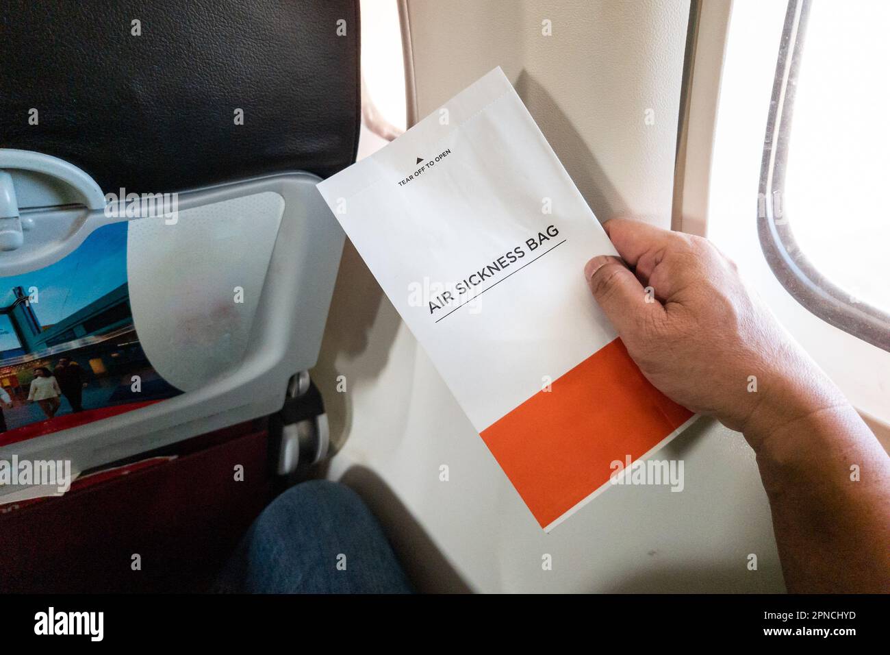 Passanger holding air sickness bag during air flight incase need to vomit Stock Photo