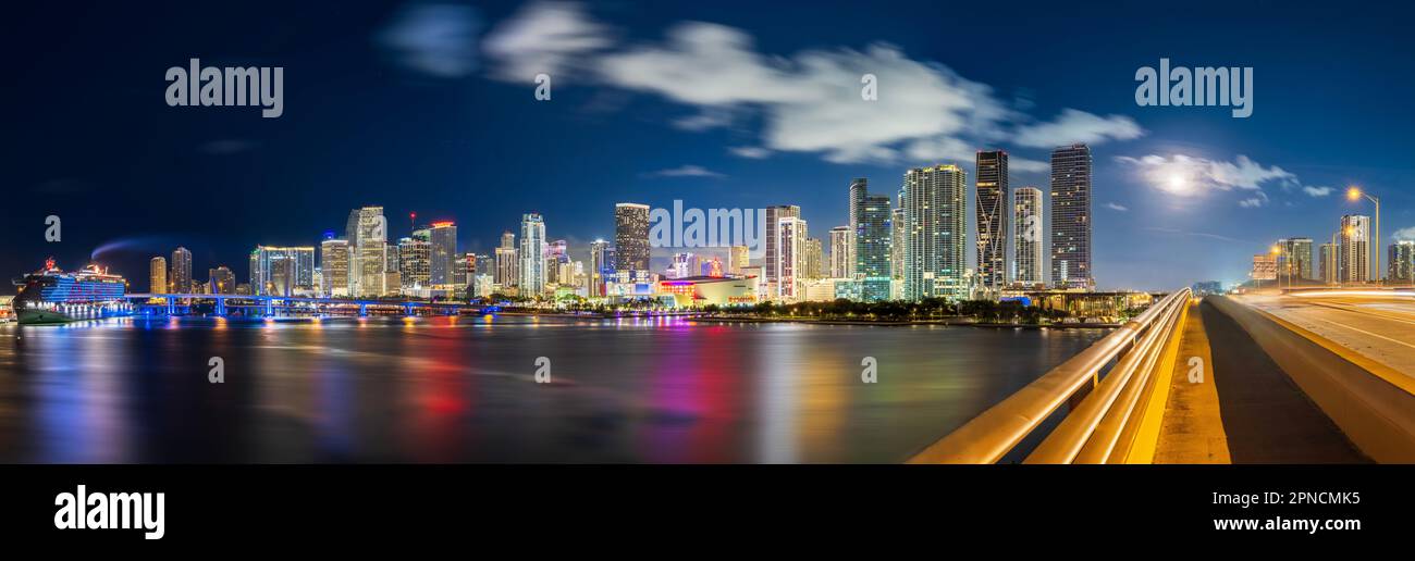 Skyline Panoramic of Miami Downtown at Dawn,  illuminated, Full Moon setting Virgin Voyage Cruise illuminated with AHOY in blue and red  Floridas East Stock Photo