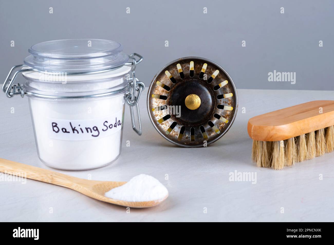 Baking soda, kitchen sink hole and wooden brush, spoon on countertop