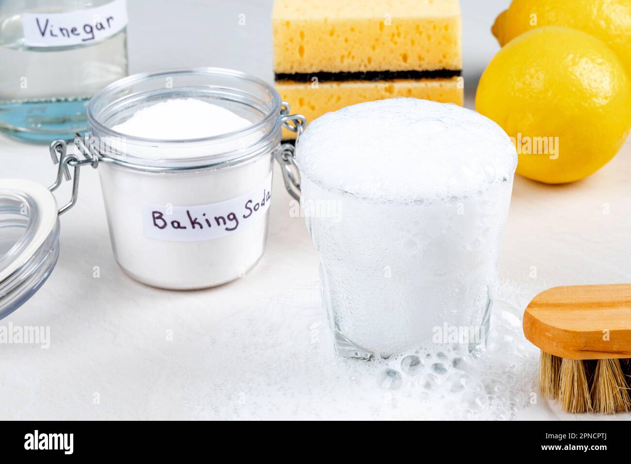 Reaction between of baking soda from a spoon with vinegar in a glass