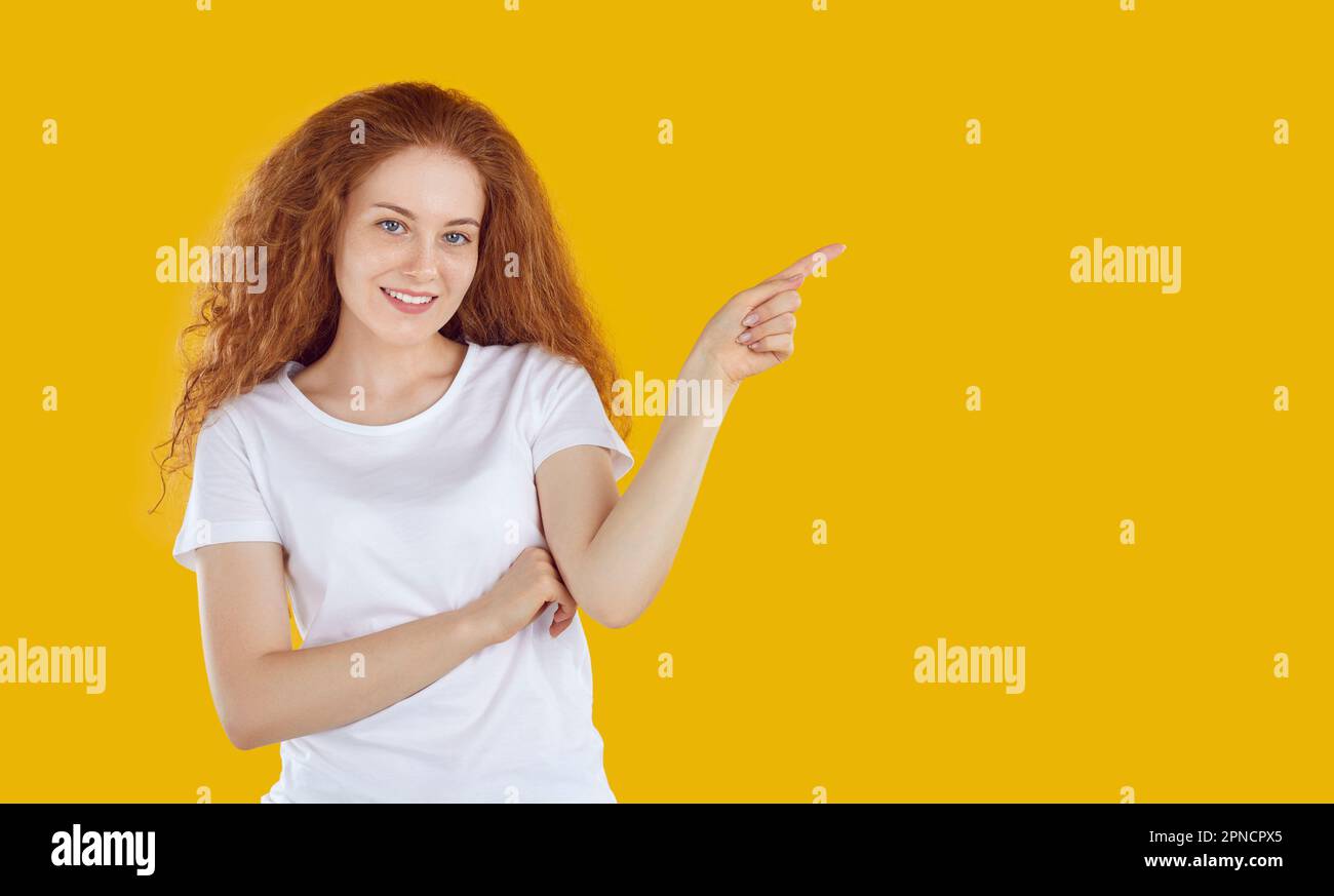 Smiling young woman pointing her finger to side Stock Photo