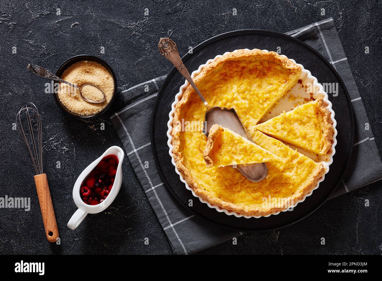 chess pie pairs a traditional butter pie crust with a sweet, custardy filling in white baking dish on concrete table with berry sauce, flat lay Stock Photo