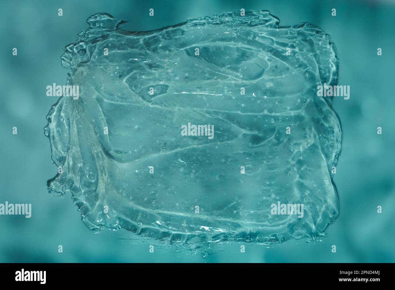 Dynamic clear gel swatch splash with air bubbles in water blue light