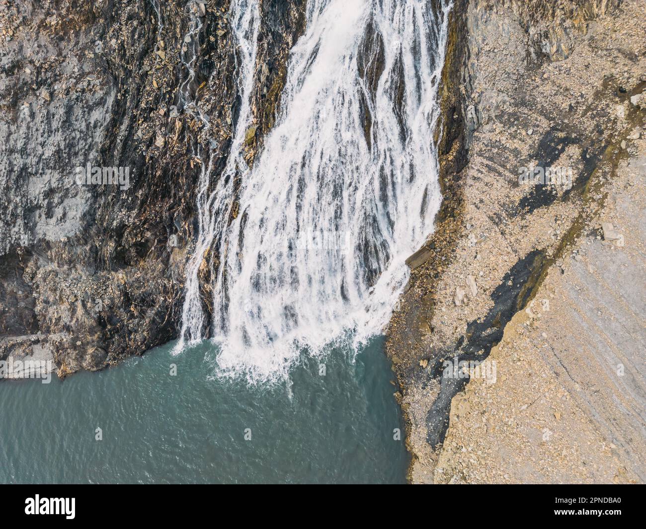 Panoramic drone shot of a waterfall flowing into Lac Chambon in French Alps Stock Photo