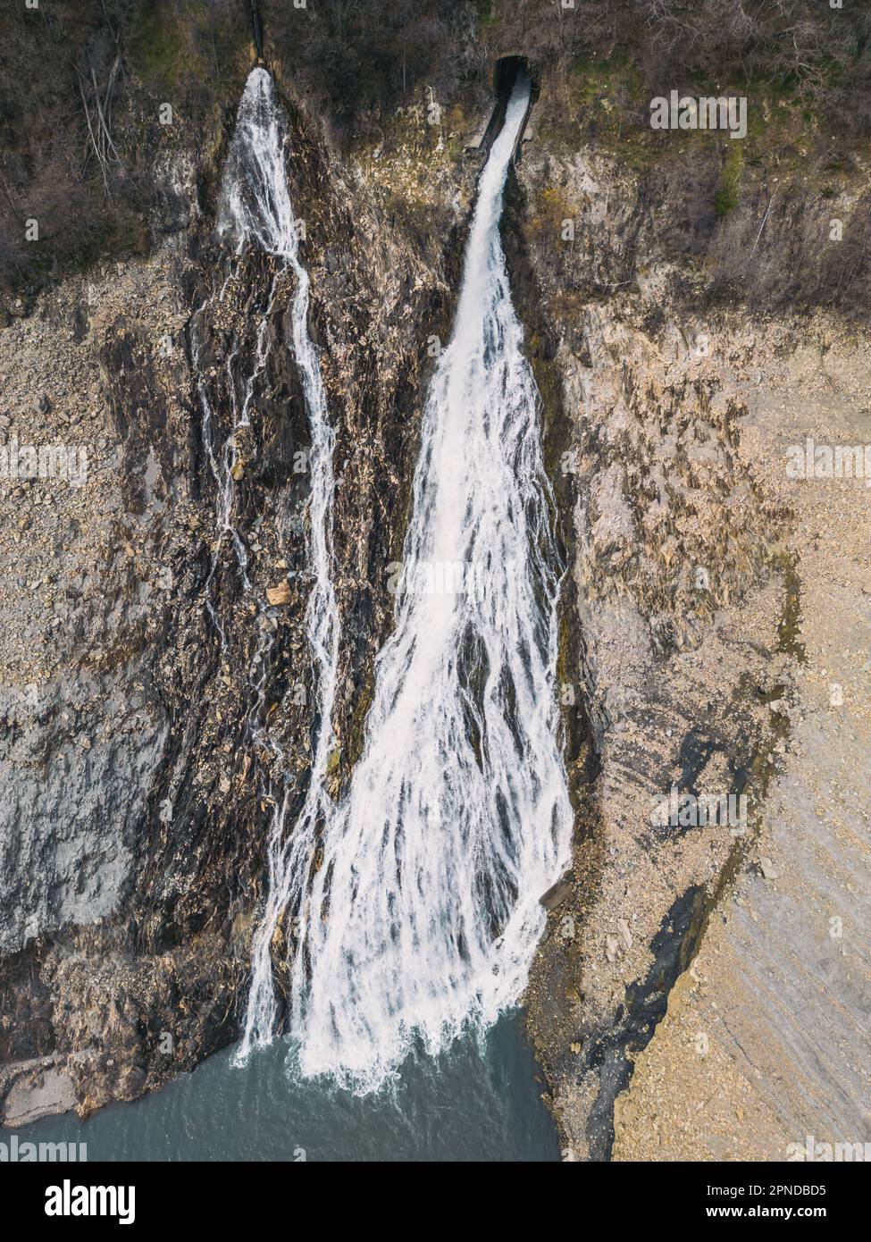Panoramic drone shot of a waterfall flowing into Lac Chambon in French Alps Stock Photo