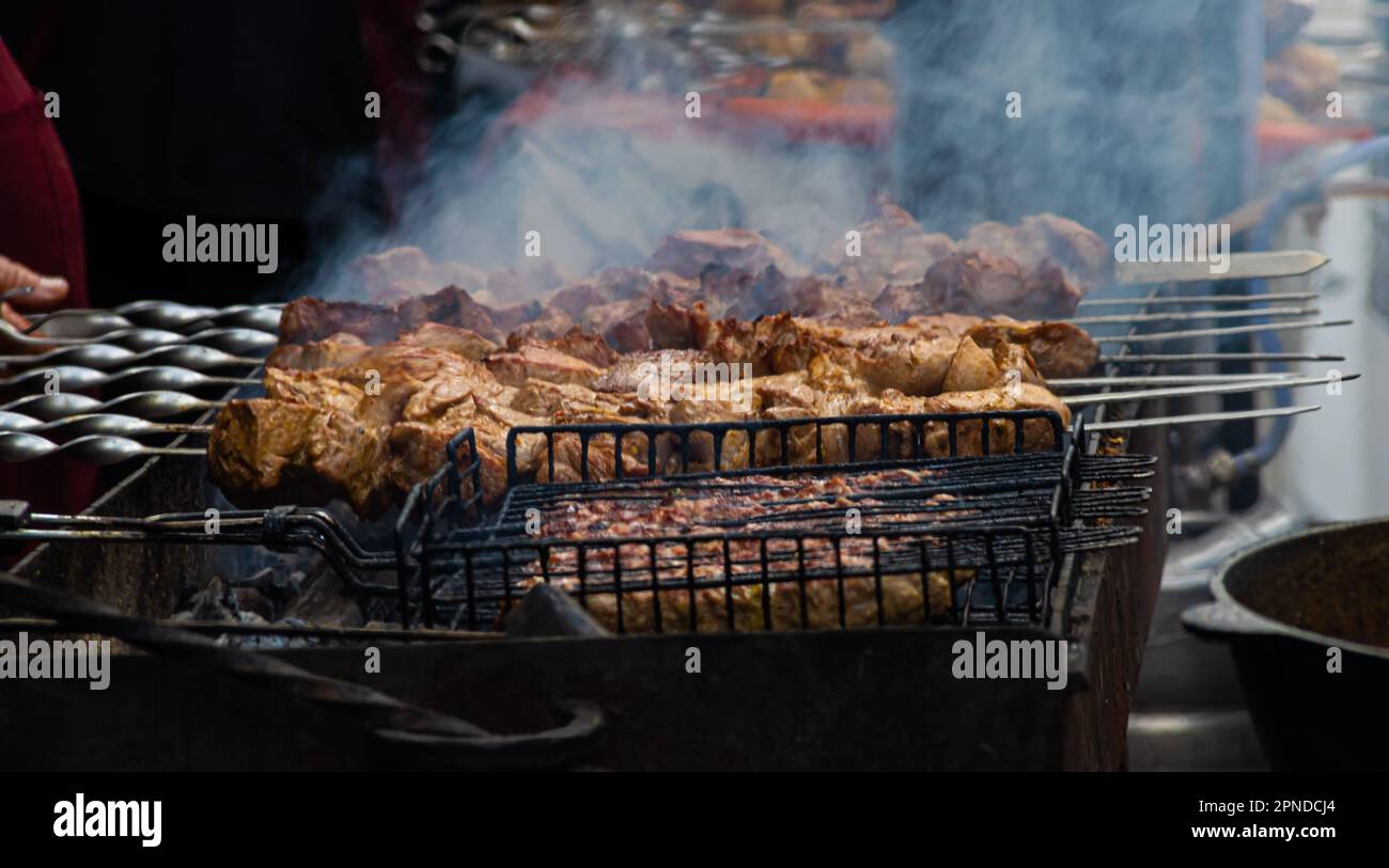 Grilling marinated shashlik preparing on a barbecue grill over charcoal.  Shashlik is a form of Shish kebab popular in Eastern Europe. Shashlyk (meaning  skewered meat) was originally made of lamb. Stock Photo