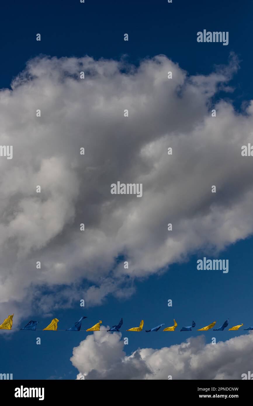Yellow and blue triangular festival flags on sky background with white ...