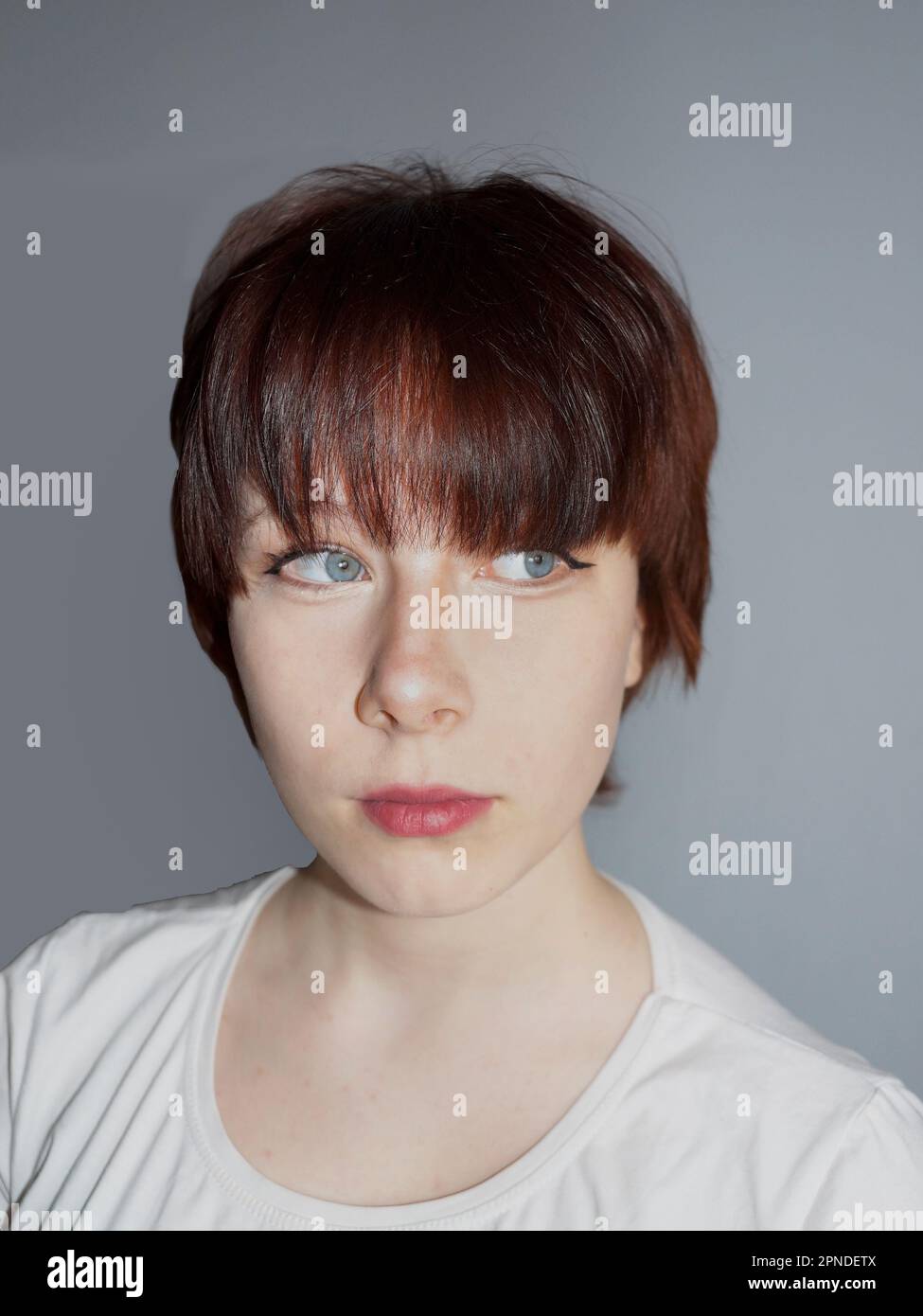 portrait of a teenage girl with short brown hair on a gray background