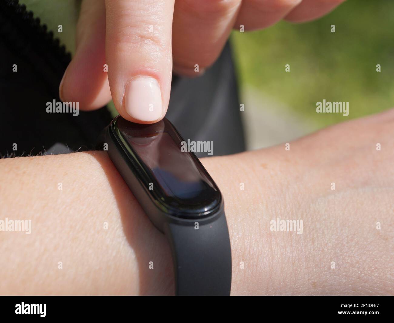 Using a fitness bracelet, a woman measures her pulse on the display of a fitness bracelet close-up Stock Photo