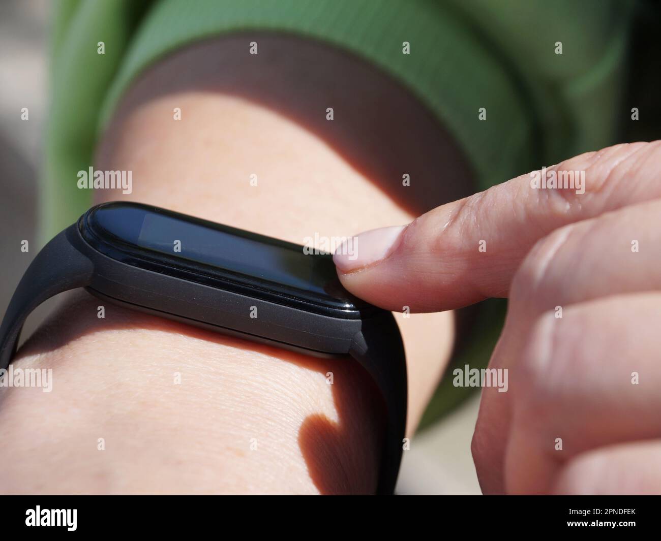Using a fitness bracelet, a woman presses her finger on the display of a fitness bracelet close-up Stock Photo