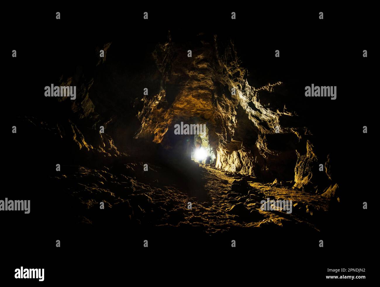 In a copper mine beneath Alderley Edge in Cheshire, people with torches caving and exploring the underground space of west mine deep below the ground Stock Photo