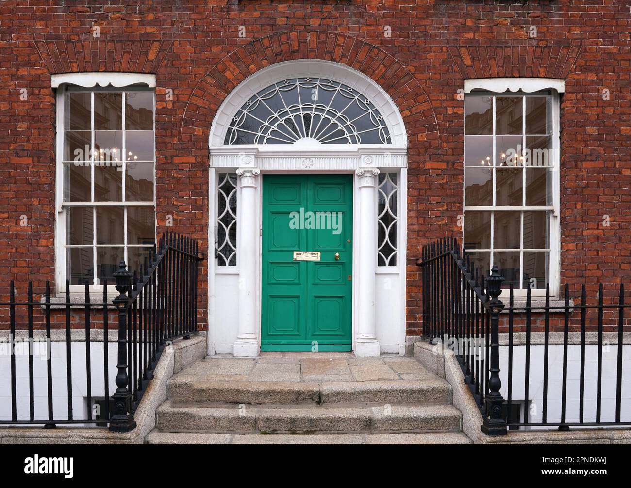 Old brick townhouse with fanlight window above door Stock