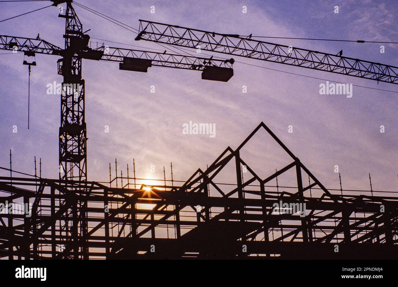 silhouette of tower cranes and steel frame building under construction ...