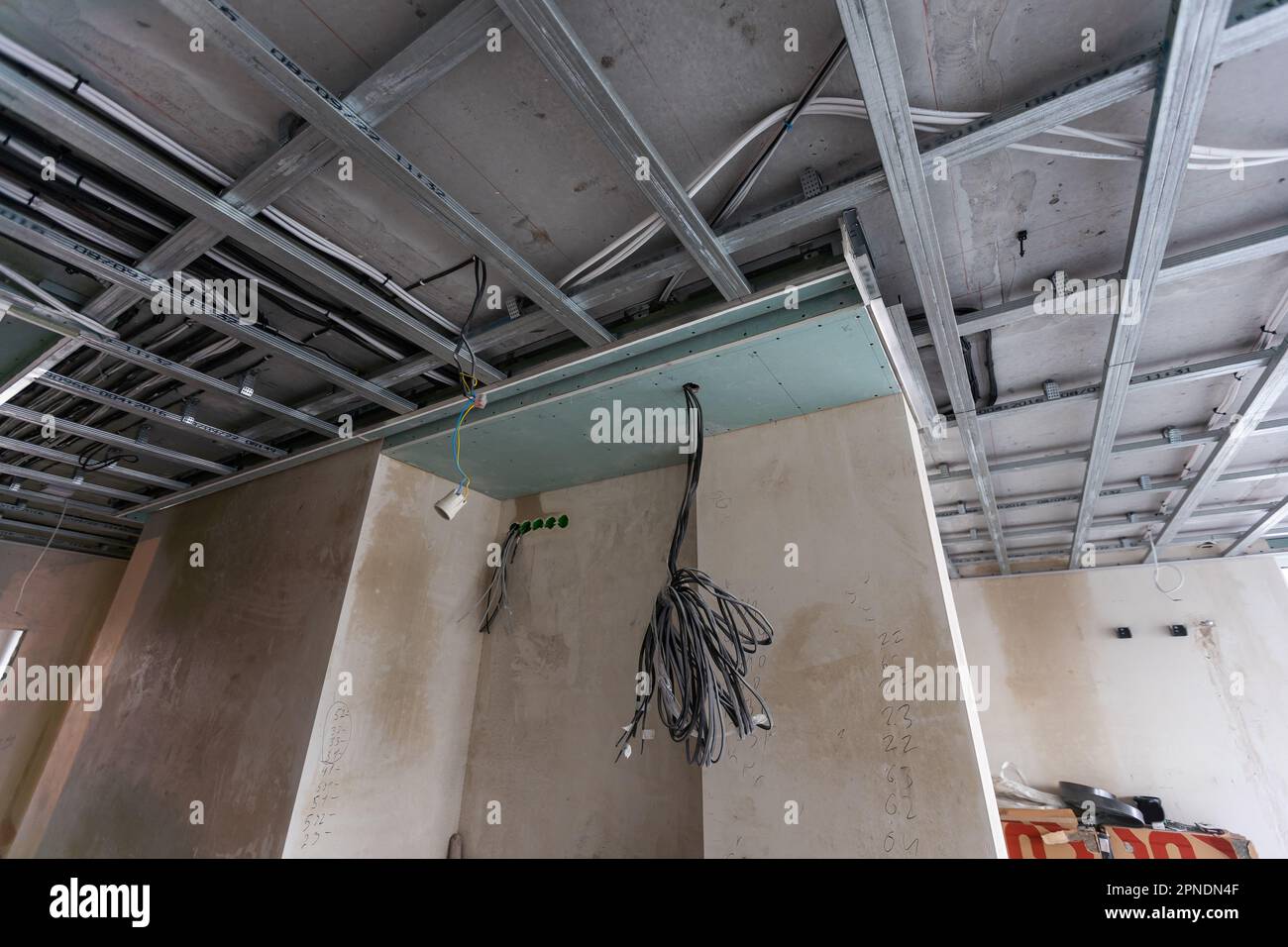 Installation of drywall. Workers are using screws and a screwdriver to