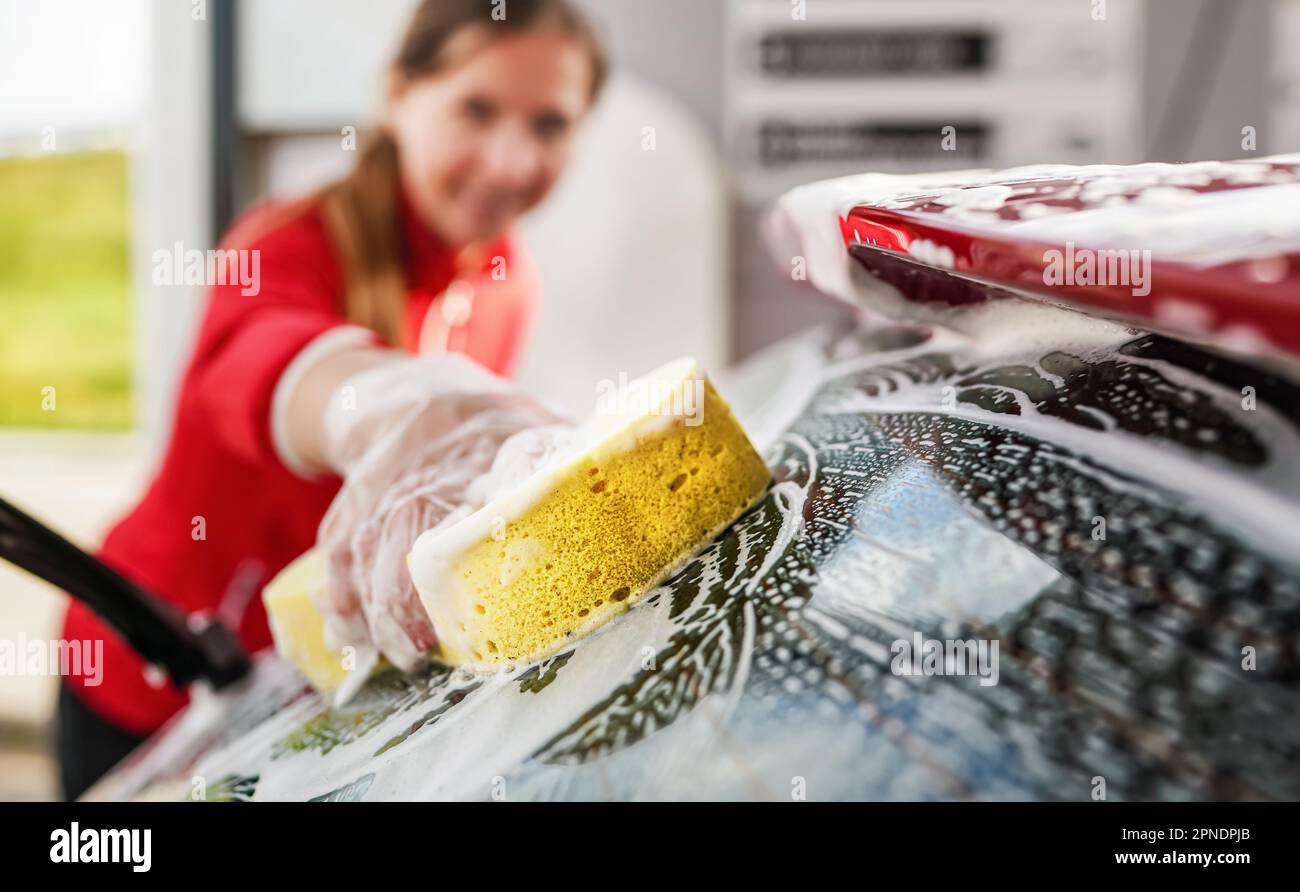 Young woman cleaning rear window of her car, closeup detail on hand in ...