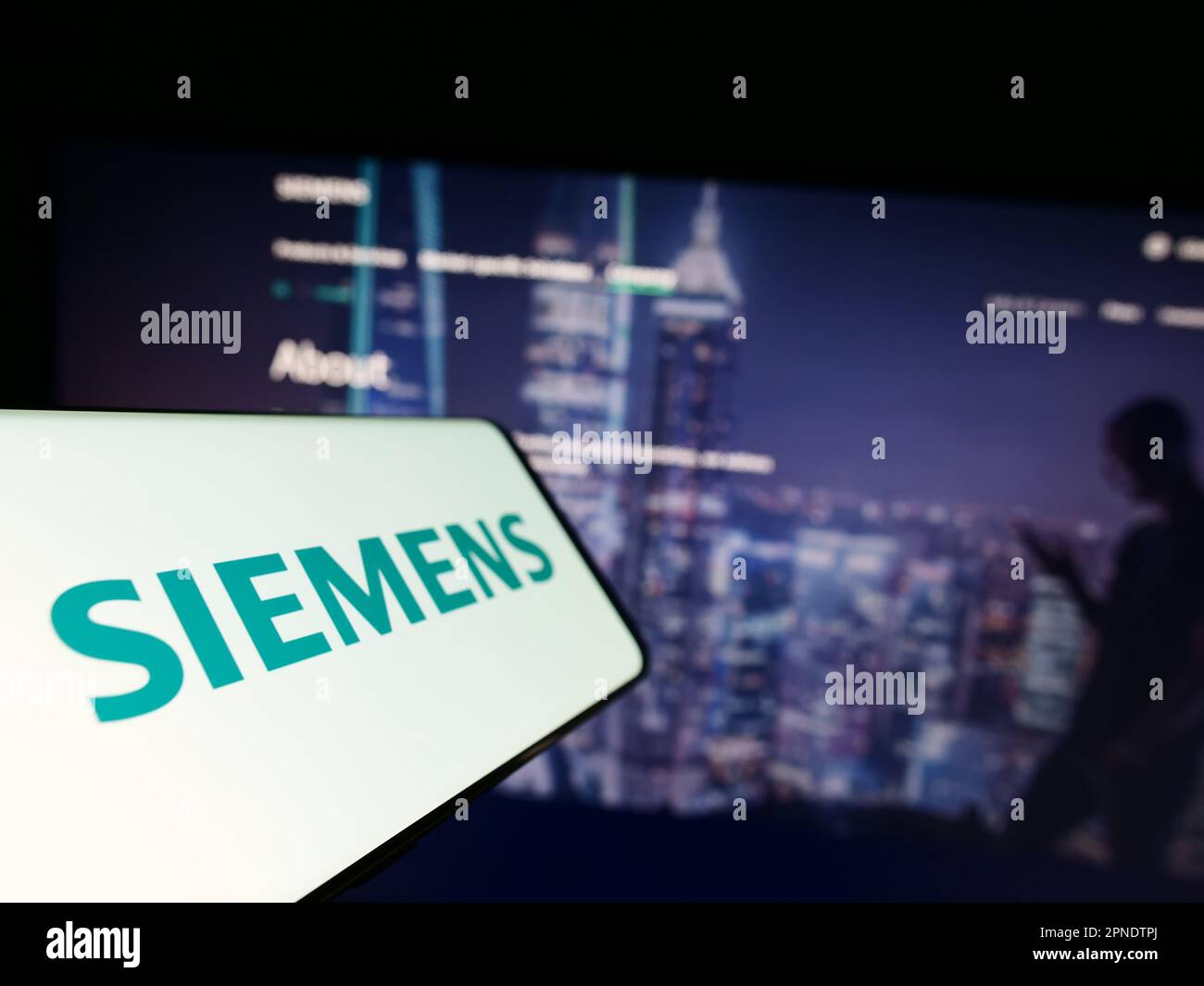 Mobile phone with logo of German conglomerate Siemens AG on screen in front of business website. Focus on center-left of phone display. Stock Photo