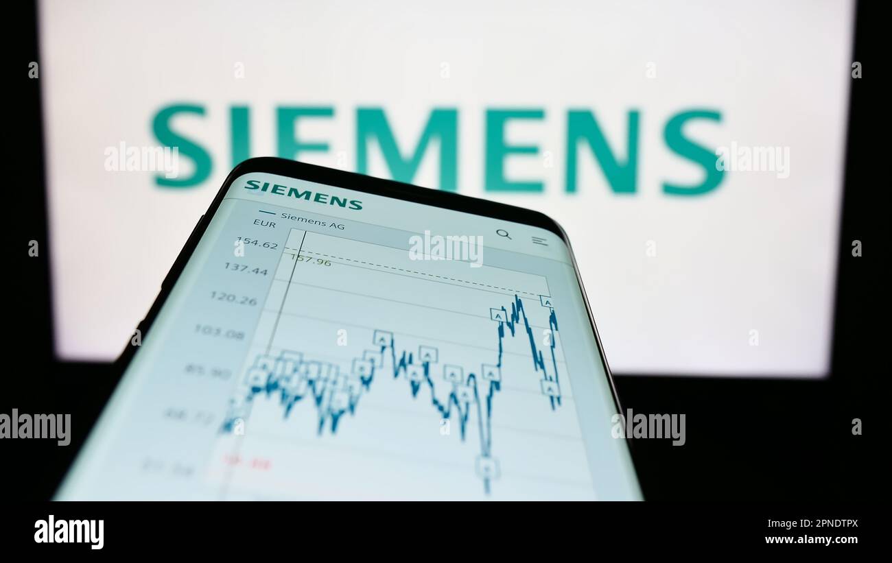 Smartphone with website of German conglomerate Siemens AG on screen in front of business logo. Focus on top-left of phone display. Stock Photo