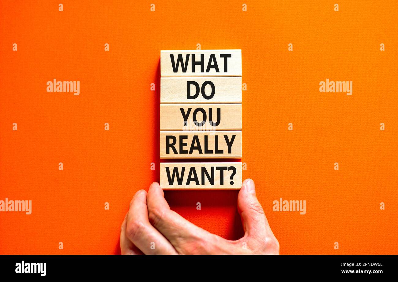 What do you really want symbol. Concept words What do you really want on wooden block. Beautiful orange table orange background. Businessman hand. Bus Stock Photo